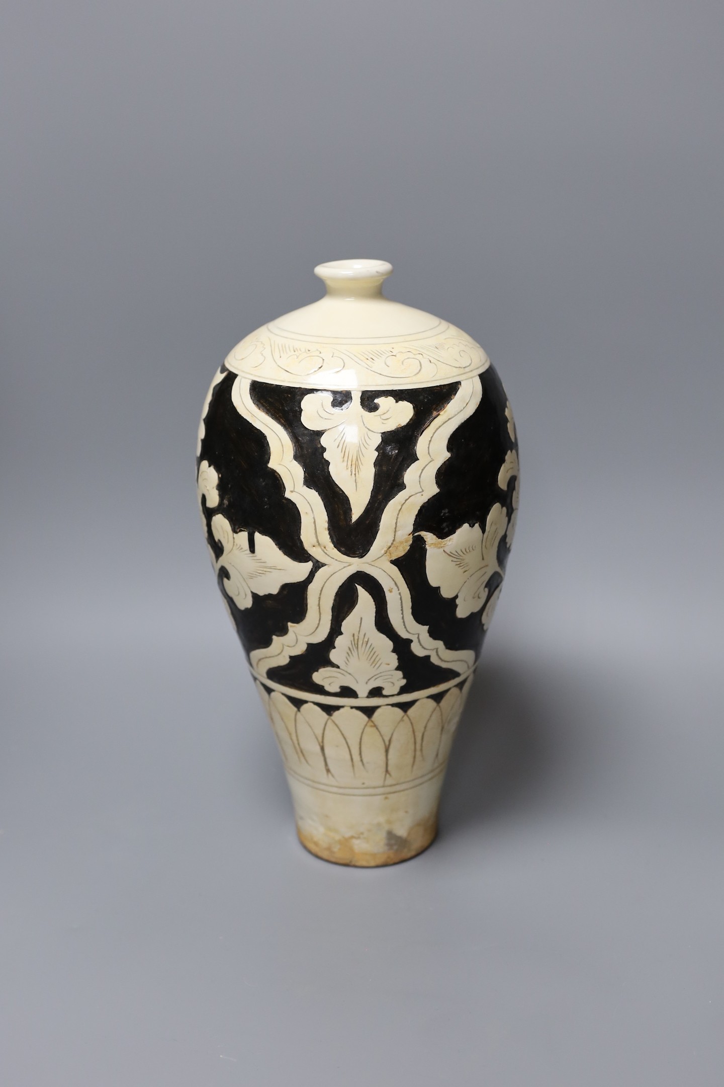 A black and white carved Chinese peony earthenware vase, 34cm tall